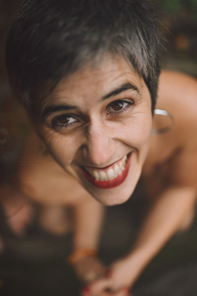 me veo con una gran sonrisa, mirando a la cámara con los ojos bien abiertos, sentada desnuda sobre una roca