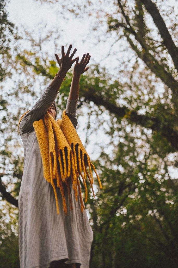 estoy con mis brazos abiertos y elevados con las palmas hacia el cielo, de pie, en un bosque rodeada de árboles