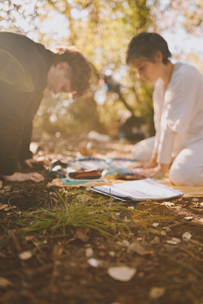 kai y yo enfrentadas estamos poniendo las palmas de la manos en la tierra, bajando la cabeza en señal de humildad, enterrando y descargando el poder